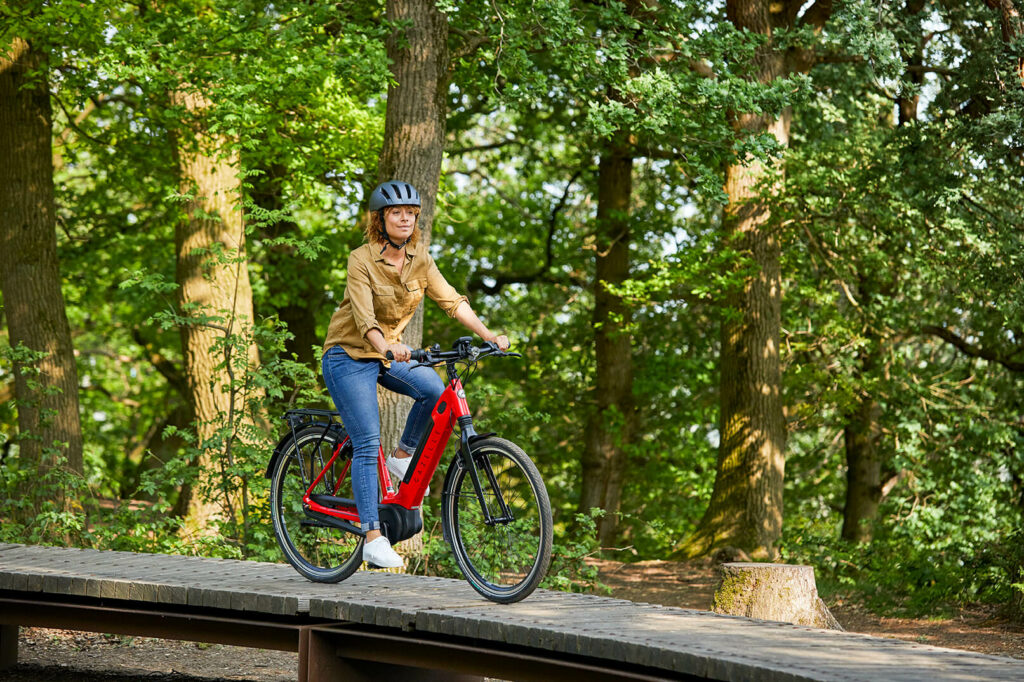 Kvinde på rød cykel i skoven