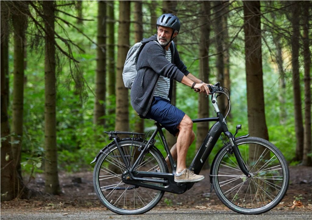 Mand med rygsæk på en cykel i skoven